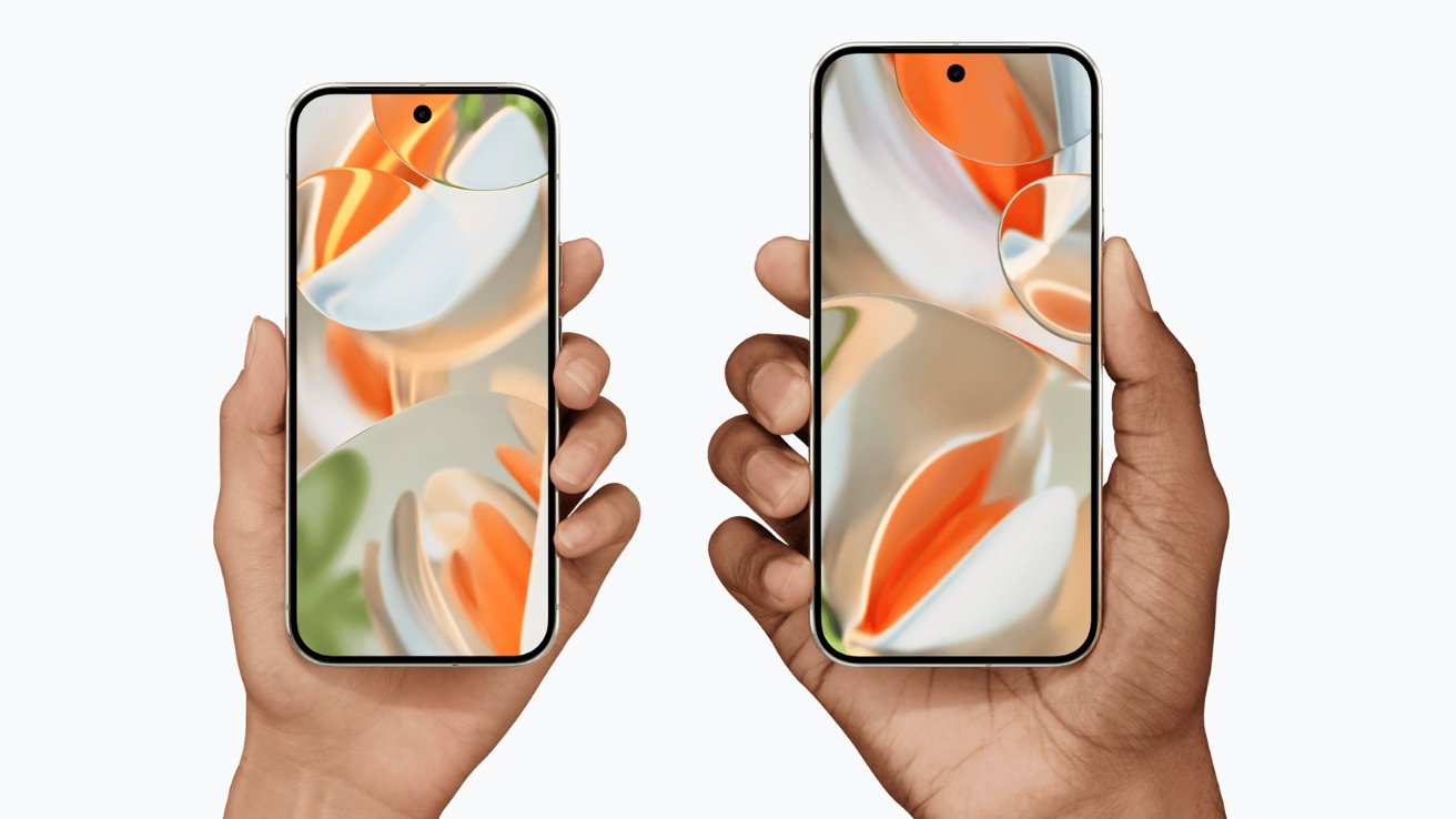Two hands holding smartphones with colorful abstract wallpaper on the screens. The left hand is light-skinned, the right hand is dark-skinned.