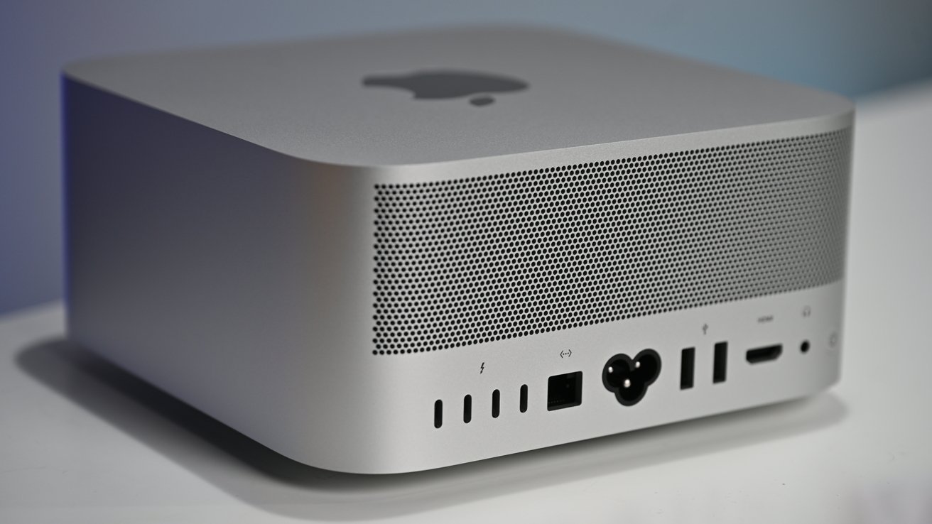 Silver rectangular computer with an Apple logo on top and various ports on the back, including USB and HDMI connections.