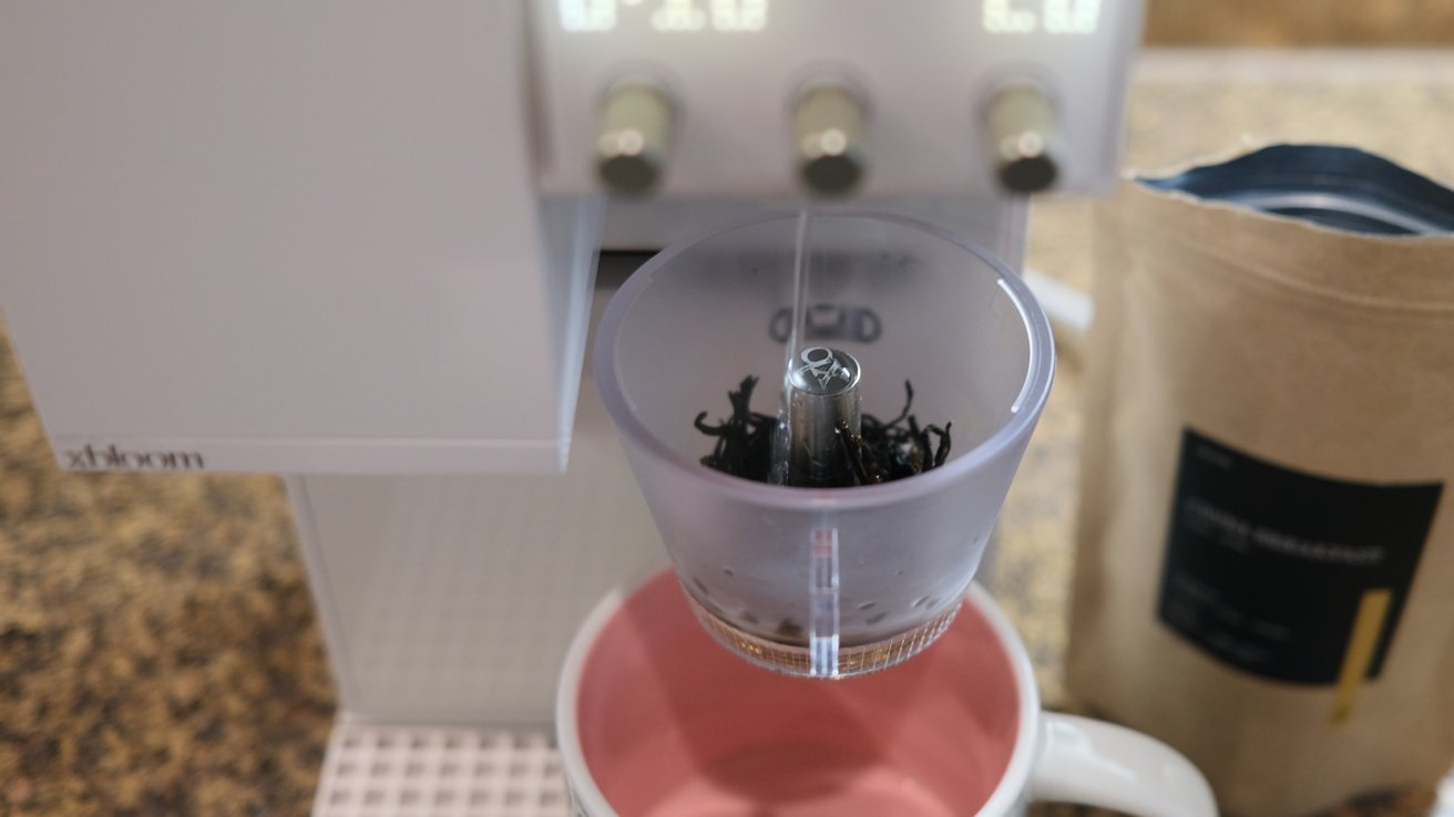Coffee machine brewing into a cup with a capsule holder and nearby packet.