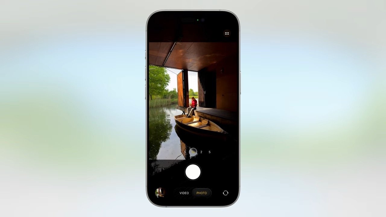 Smartphone display showing a person sitting in a boat inside a wooden structure, surrounded by calm water and greenery.